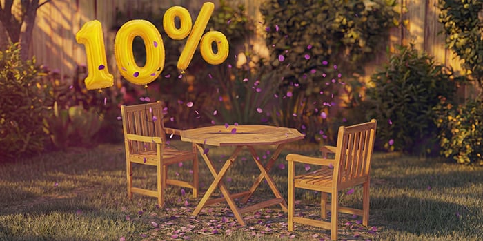 Houten buiteneettafel van hout met twee bijpassende stoelen in een tuinsetting, versierd met roze confetti en gouden ballonnen met “10% korting”, die een seizoensuitverkoop van buiten-eetmeubelen benadrukken.